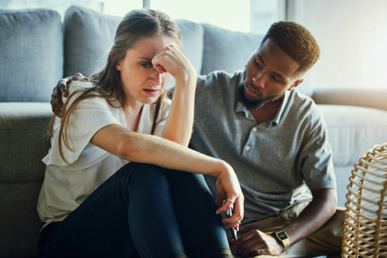 Depression, sad and compassion with a man and woman comforting or consoling in a home living room.